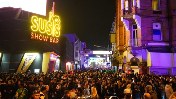 Feiernde gehen über den Beatles-Platz und die Große Freiheit in der Silvesternacht im Hamburger Stadtteil St. Pauli. © picture alliance / dpa Foto: Marcus Brandt