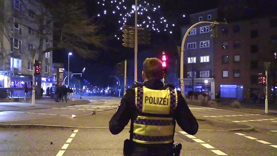 Ein Polizist sichert in der Silvesternacht eine Straße in Hamburg. © TV Newskontor Foto: Screenshot