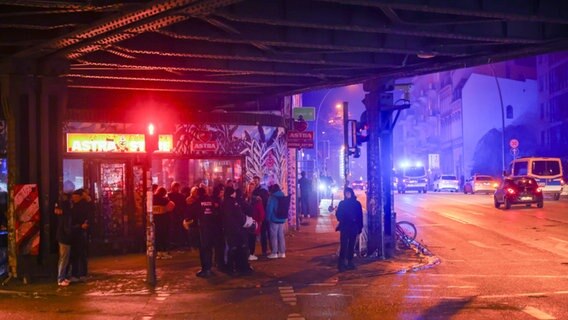 Vor den Astra-Stuben unter der Sternbrücke stehen Feiernde und Polizeibeamte. © picture alliance/dpa | Christian Charisius Foto: Christian Charisius