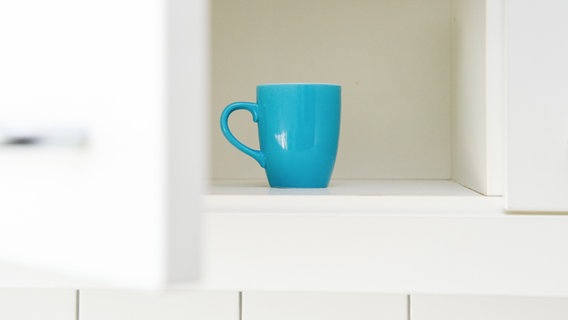 Eine einzelne Tasse steht in einem Küchenschrank. © dpa Themendienst Foto: Karo Kraemer