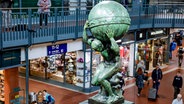 Passanten betrachten die enthüllte Atlas-Skulptur im Hamburger Hauptbahnhof. © picture alliance / dpa Foto: Axel Heimken