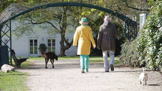 Zwei Menschen gehen mit ihren Hunden im Hirschpark spazieren. © IMAGO / Nikita Foto: IMAGO / Nikita