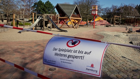 Schild mit Aufschrift "Der Spielplatz ist bis auf Weiteres gesperrt!" hängt an einem Absperrband am Eingang eines Spielplatzes in Hamburg © dpa-Bildfunk Foto: Christian Charisius
