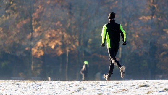Ein Mann joggt durch den winterlichen Hamburger Stadtpark. © dpa Foto: Markus Scholz