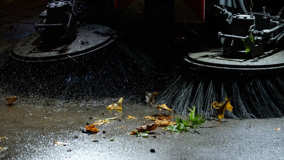 Eine Kehrmaschine der Stadtreinigung fegt nasse Blätter von der Straße. © dpa Foto: Jonas Walzberg
