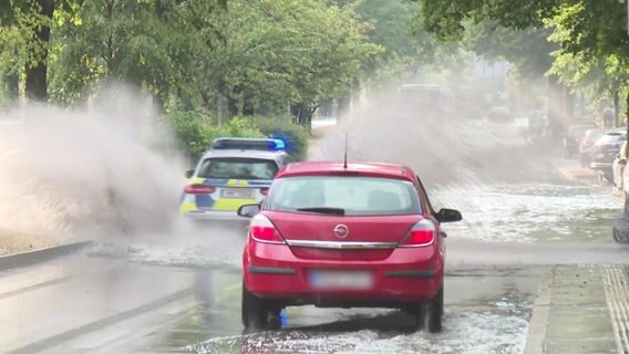 Samochody jeżdżą po zalanej drodze i rozpylają wodę.  © TV News Kontor Fot.: Zrzut ekranu