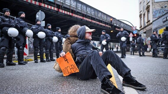 Aus Protest gegen den Abriss der Sternbrücke haben sich zwei Demonstrierende auf die Max-Brauer-Allee gesetzt. © picture alliance/dpa Foto: Christian Charisius