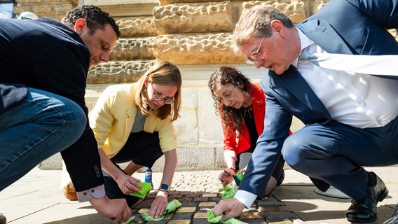Bürgerschaftsabgeordnete putzen anlässlich des 80. Jahrestages der Befreiung vom Nationalsozialismus die Stolpersteine vor dem Eingang des Hamburger Rathauses. © picture alliance / dpa Foto: Jonas Walzberg