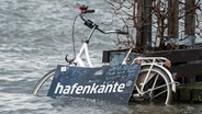 Ein Fahrrad steht während einer Sturmflut beim Hochwasser der Elbe auf dem überschwemmten Fischmarkt in Hamburg. © picture alliance / dpa Foto: Daniel Bockwoldt