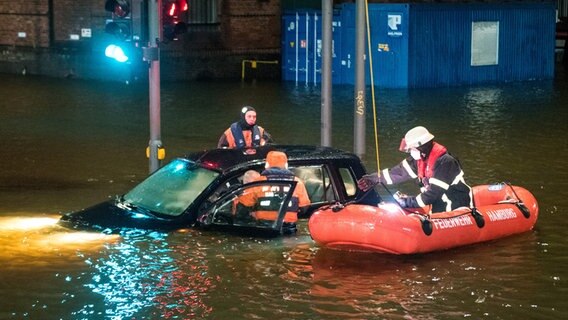 Einsatzkräfte der Feuerwehr retten in der Hamburger Speicherstadt während einer Sturmflut einen Mann aus einem Auto. © picture alliance/dpa Foto: Daniel Bockwoldt