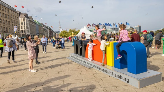 Touristinnen und Touristen machen mit dem "moin"-Schild am Jungfernstieg Fotos. © NDR Foto: Axel Herzig