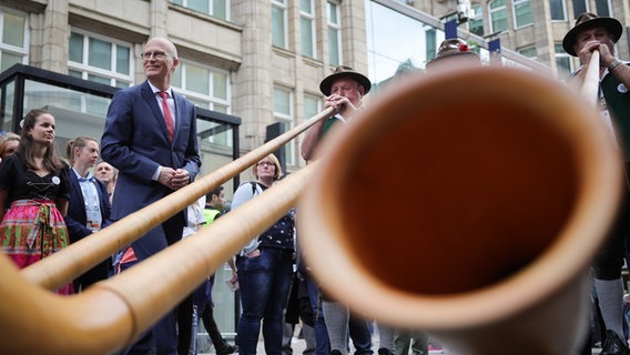 Hamburgs Bürgermeister Peter Tschentscher (l.) trifft bei einem Rundgang über das Bürgerfest zum Tag der Deutschen Einheit auf eine Gruppe Alphornbläser. © picture alliance / dpa Foto: Christian Charisius