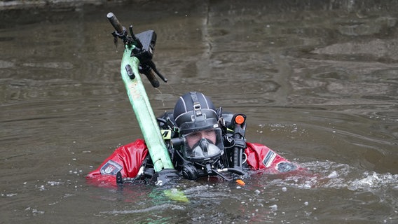 A diver from the fire brigade brings an e-scooter to the banks of the Alster in Hamburg.  © picture alliance / dpa Photo: Marcus Brandt