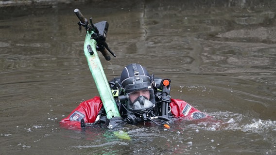 Ein Taucher der Feuerwehr bringt einen E-Scooter ans Ufer der Alster in Hamburg. © picture alliance / dpa Foto: Marcus Brandt