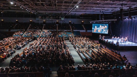 Trauergäste sitzen in der Alsterdorfer Sporthalle bei bei einer Gedenkveranstaltung der Zeugen Jehovas für die Opfer eine Amoklaufs. © picture alliance/dpa/Jehovas Zeugen in Deutschland, | J.Z. Foto: Jehovas Zeugen