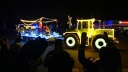 Ein dekorierter Traktor fährt an Schaulustigen vorbei. Mit 35 weihnachtlich geschmückten Traktoren haben Landwirte von Stormarn aus Spenden zum Universitätsklinikum Hamburg-Eppendorf gebracht. © picture alliance / dpa Foto: Jonas Walzberg
