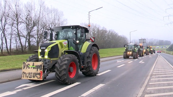 Bauern fahren über eine Straße mit Plakaten vor den Traktoren gespannt. © TNN Foto: TNN