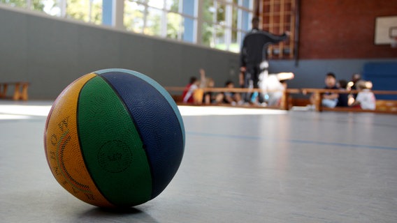 Ein Basketball liegt in einer Sporthalle in Hamburg auf dem Hallenboden. © picture alliance / dpa Themendienst Foto: Mascha Brichta