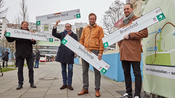 Klaus Uphoff, Projektleiter Hamburger Hochbahn, Henrik Falk, Hochbahn-Chef, Anjes Tjarks (Bündnis 90/Die Grünen), Verkehrssenator, und David Claus, Bürgerbeteiligung Hamburger Hochbahn (v.l.n.r.), stehen während einer Pressekonferenz zur neuen U-Bahnlinie U5 in der Gründgensstraße in Steilshoop mit Hinweisschildern mit den zukünftigen Namen der U-Bahnstationen City Nord (Stadtpark), Barmbek Nord, Steilshoop und Bramfeld. © picture alliance / dpa Foto: Georg Wendt