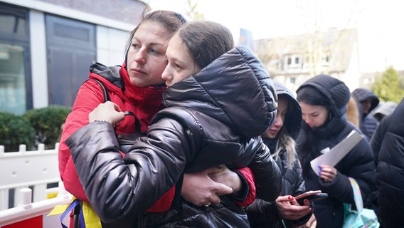 Eine Mutter umarmt ihre Tochter in der Warteschlange vor der Zentralen Ausländerbehörde.  Foto: picture alliance/dpa | Marcus Brandt