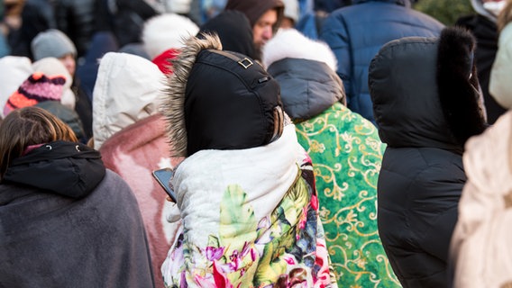 Ukrainische Flüchtlinge warten in Decken gehüllt vor dem Amt für Migration auf ihre Registrierung. © dpa Foto: Daniel Bockwoldt