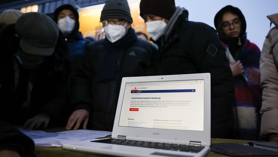 Helfer unterstützen ukrainische Geflüchtete in Hamburg mit ihren Computern beim Ausfüllen von Online-Anträgen. © dpa Foto: Christian Charisius