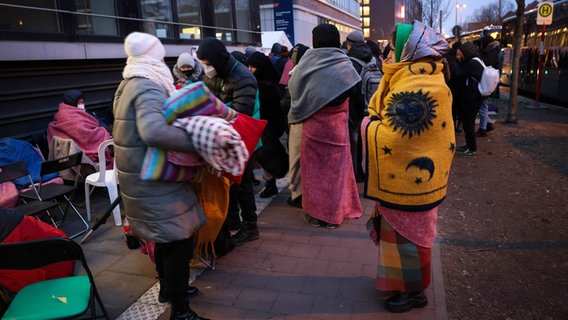 Menschen, die aus der Ukraine geflohen sind, warten am Donnerstagmorgen vor dem Amt für Migration in Hamburg. © dpa Foto: Christian Charisius