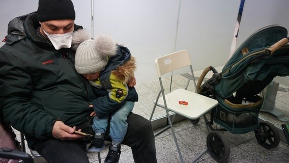 Ein Vater und sein dreijähriger Sohn, geflüchtet aus Ukraine, sitzen in einem Raum am Hamburger Hauptbahnhof. © dpa Foto: Marcus Brandt