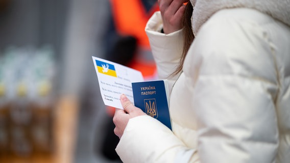 Eine junge Frau aus der Ukraine mit ihrem Pass in der Hand in Hamburg. © picture alliance / dpa Foto: Daniel Reinhardt
