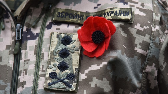 Eine rote Mohnblume ist an einer ukrainischen Militärunform befestigt. © picture alliance / AA Foto: Pavlo Palamarchuk