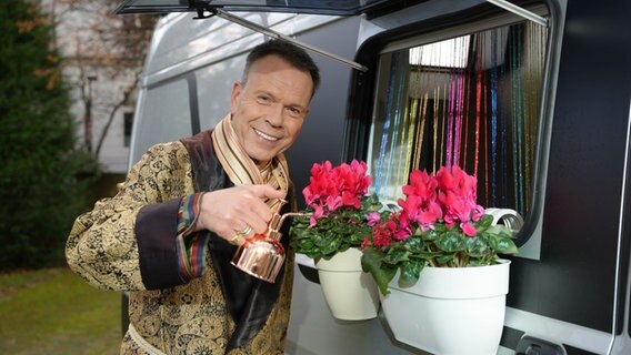 Ulf Ansorge gießt Blumen in einem Blumenkasten an einem Wohnmobil. © NDR Foto: Alexander Dietze