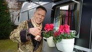 Ulf Ansorge gießt Blumen in einem Blumenkasten an einem Wohnmobil. © NDR Foto: Alexander Dietze