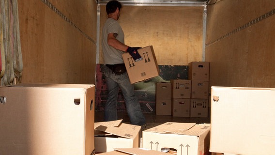Ein Mann trägt bei einem Umzug einen Karton in einen Lastwagen. © picture alliance / dpa Themendienst Foto: Kai Remmers
