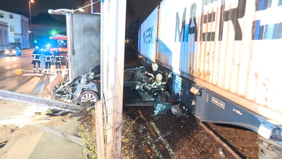 Ein BMW klemmt nach einem Unfall zwischen einer Leitplanke und einem Zug. © NonstopNews / Screenshot Foto: Screenshot