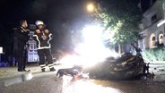 Zwei Einsatzkräfte der Feuerwehr und der Polizei stehen neben einem ausgebranntem Motorrad in Winterhude. © Nonstopnews Foto: Screenshot