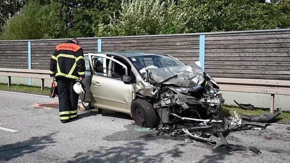 Ein Feuerwehrmann schaut sich nach einem Unfall in Hamburg-Neuenfelde das Wrack eines Autos an. © DSLR News 