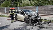 Ein Feuerwehrmann schaut sich nach einem Unfall in Hamburg-Neuenfelde das Wrack eines Autos an. © DSLR News 