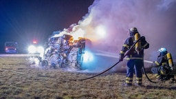 Einsatzkräfte der Feuerwehr löschen ein brennendes Auto. © picture alliance/dpa Foto: Rene Schröder