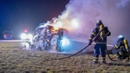 Einsatzkräfte der Feuerwehr löschen ein brennendes Auto. © picture alliance/dpa Foto: Rene Schröder