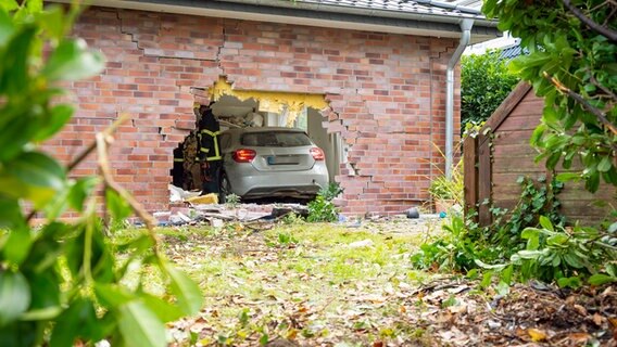 Nach einem Unfall in Lurup steht ein Auto in einem Haus, dessen Fassade stark beschädigt ist. © picture alliance/dpa Foto: Jonas Walzberg