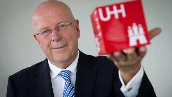 Dieter Linzen, president van de universiteit van Hamburg, toont een kubus met het logo van de universiteit erop.  © foto alliantie / Christian Charicius / DPA 