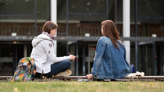 Zwei Studentinnen sitzen auf dem Campus der Universität Hamburg vor dem Audimax. © dpa Foto: Daniel Reinhardt