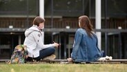 Zwei Studentinnen sitzen auf dem Campus der Universität Hamburg vor dem Audimax. © dpa Foto: Daniel Reinhardt