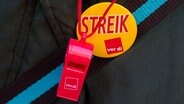 Eine Teilnehmerin eines Warnstreiks trägt einen Button mit der Aufschrift "Streik" und eine Trillerpfeife an ihrer Jacke. © picture alliance / dpa Foto: Daniel Bockwoldt