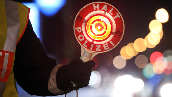 Ein Polizist hält ein Kelle mit der Aufschrift "Halt Polizei" hoch. © dpa Foto: Bodo Marks