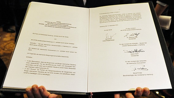 Eine Mitarbeiterin hält in Hamburg im Rathaus den zuvor von Hamburgs Erstem Bürgermeister Scholz und Vertretern von islamischen Religionsgemeinschaften unterzeichneten Vertrag in den Händen. © dpa Foto: Angelika Warmuth