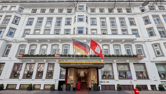 Ein Concierge steht vor dem Eingang des Hamburger Hotels "Vier Jahreszeiten". © dpa Foto: Georg Wendt
