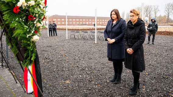 Hamburgs Zweite Bürgermeisterin Katharina Fegebank (Grüne) und Bürgerschaftspräsidentin Carola Veit (SPD) stehen am Volkstrauertag vor einem Kranz auf dem Gelände der KZ-Gedenkstätte Neuengamme. © dpa Foto: Daniel Bockwoldt