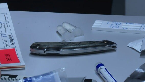 Ein Messer und Drogen liegen auf einem Tisch. © Tele News Network Foto: Screenshot