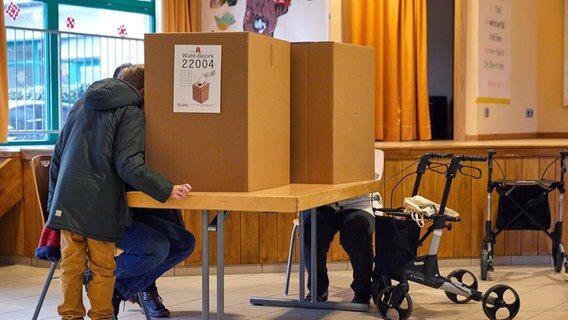 Wähler mit Kind und Wählerin mit Rollator geben in einem Wahllokal in Hamburg-Lurup ihre Stimme für die Bürgerschaftswahl ab © dpa Foto: Georg Wendt